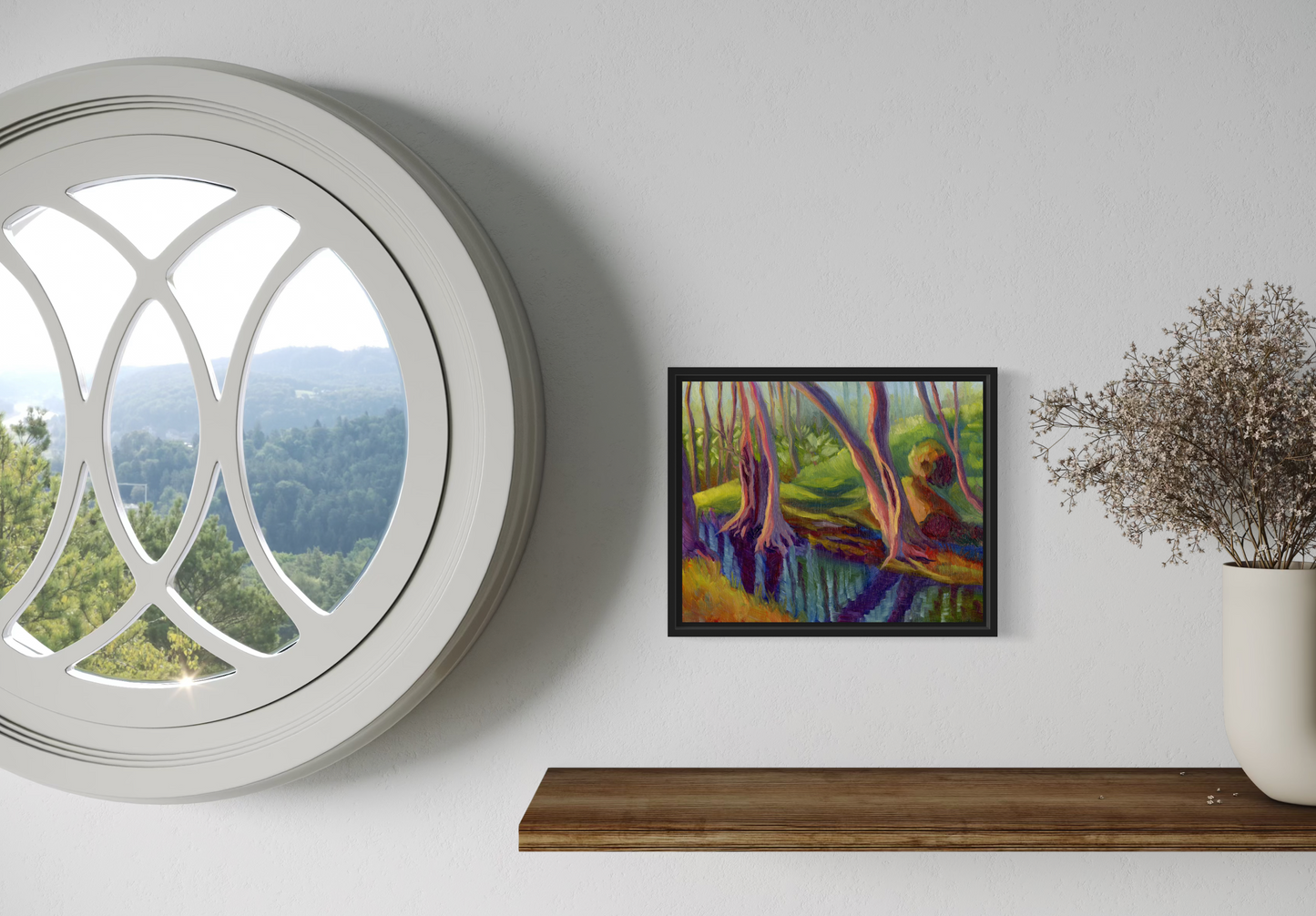 Framed artwork on a wall next to a round window with a view of trees.