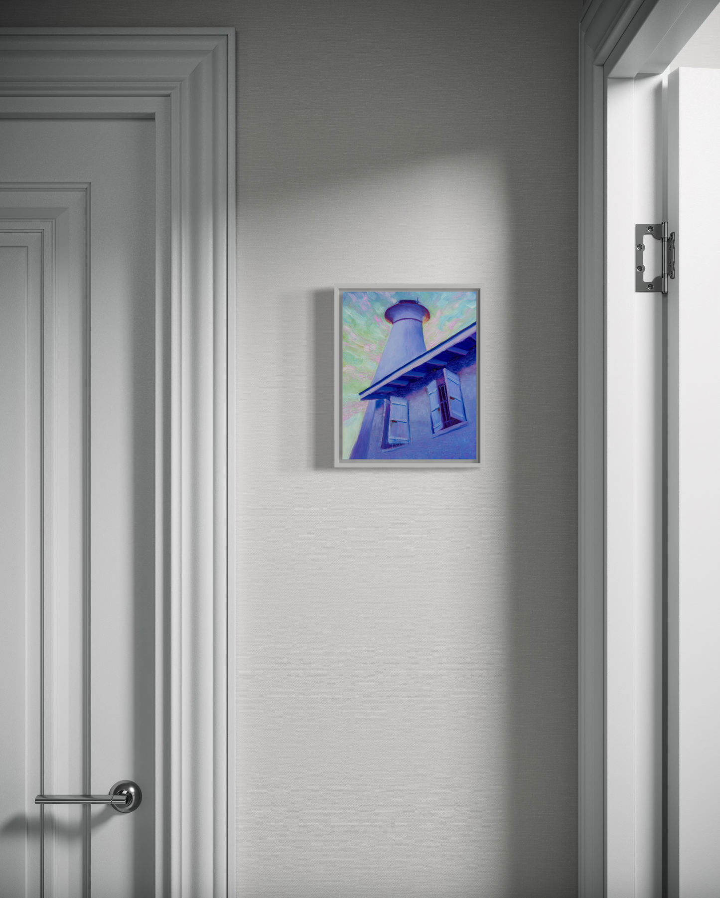 Framed artwork of a lighthouse on a white wall next to a door.