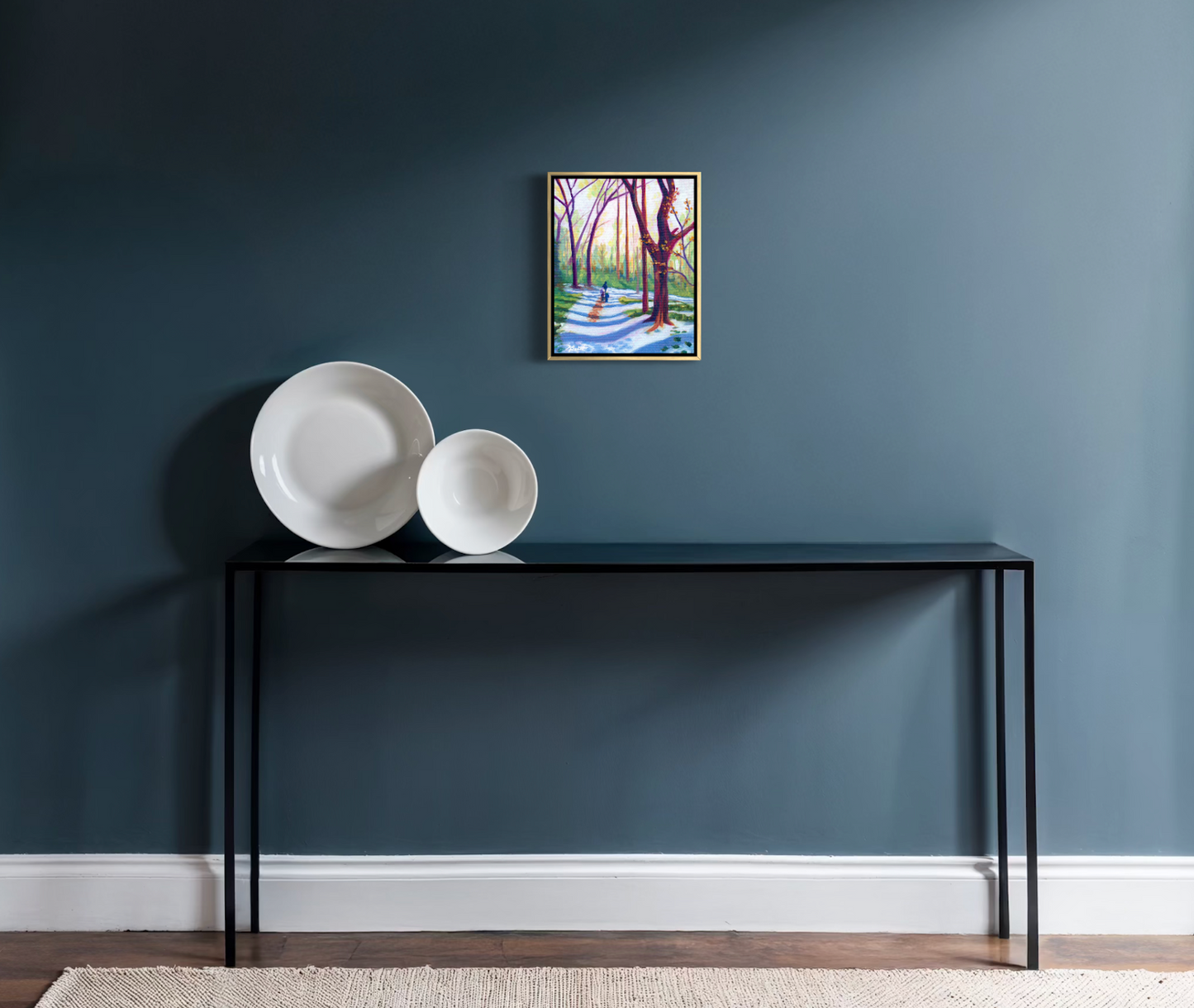Console table with decorative plates against a blue wall with a framed picture.