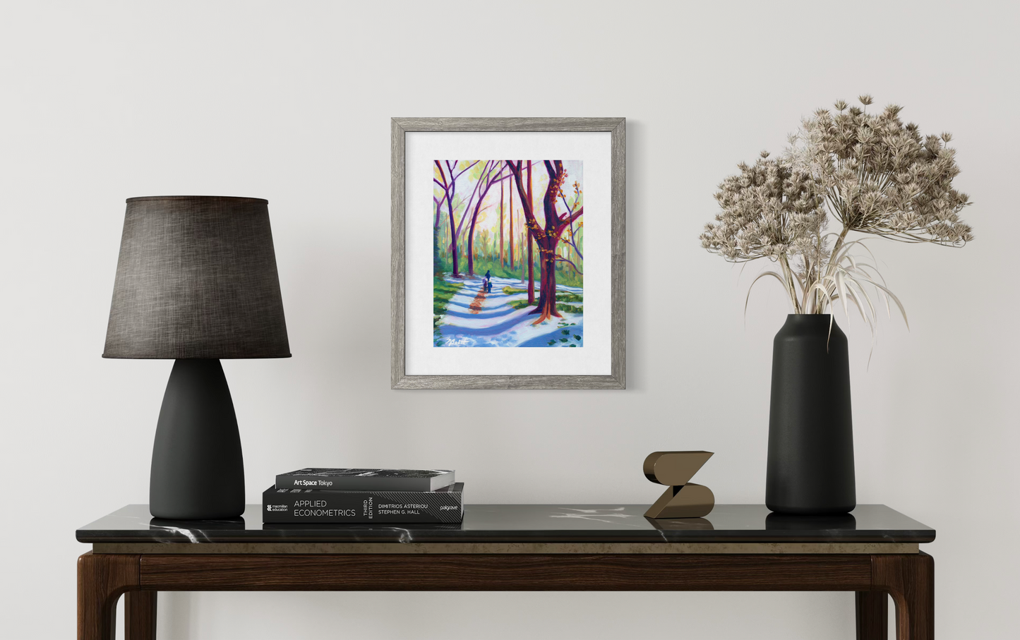 Framed artwork on a wall above a wooden console table with decorative items.
