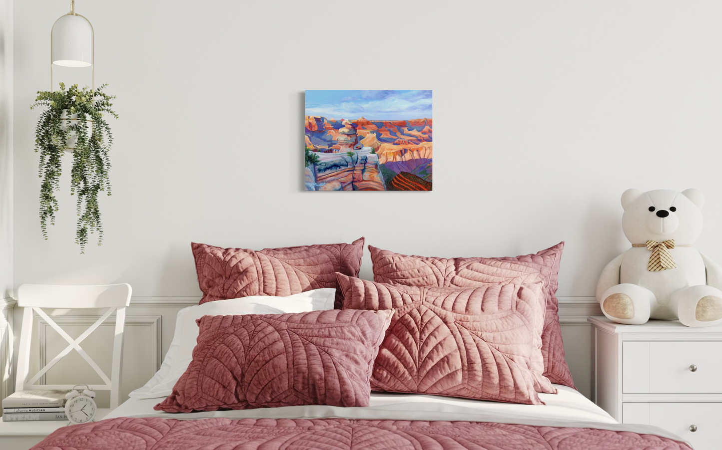 Pink quilted bedding set on a bed with a teddy bear and plant in the room.