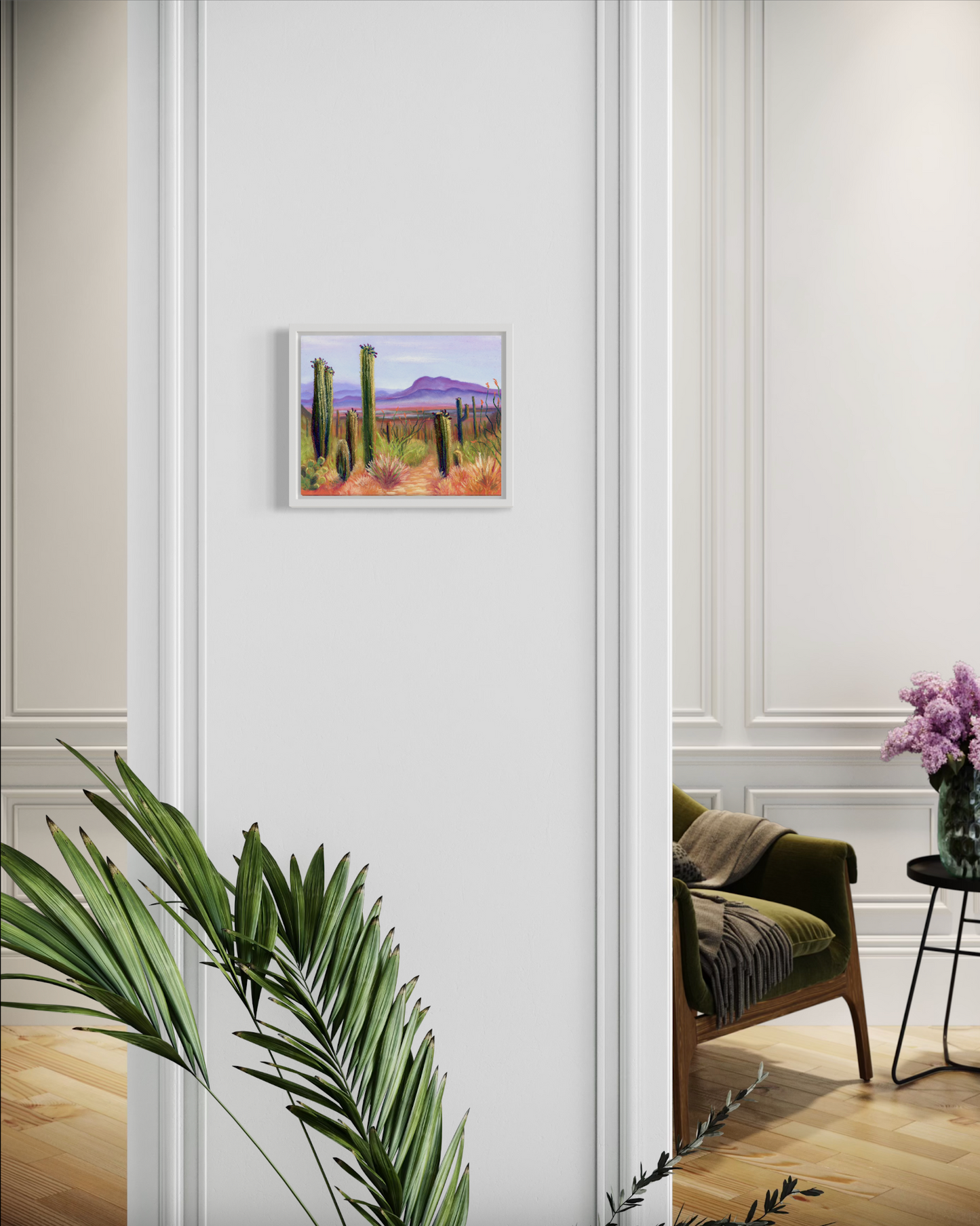 Framed artwork of a desert landscape on a wall in a room with decor elements.