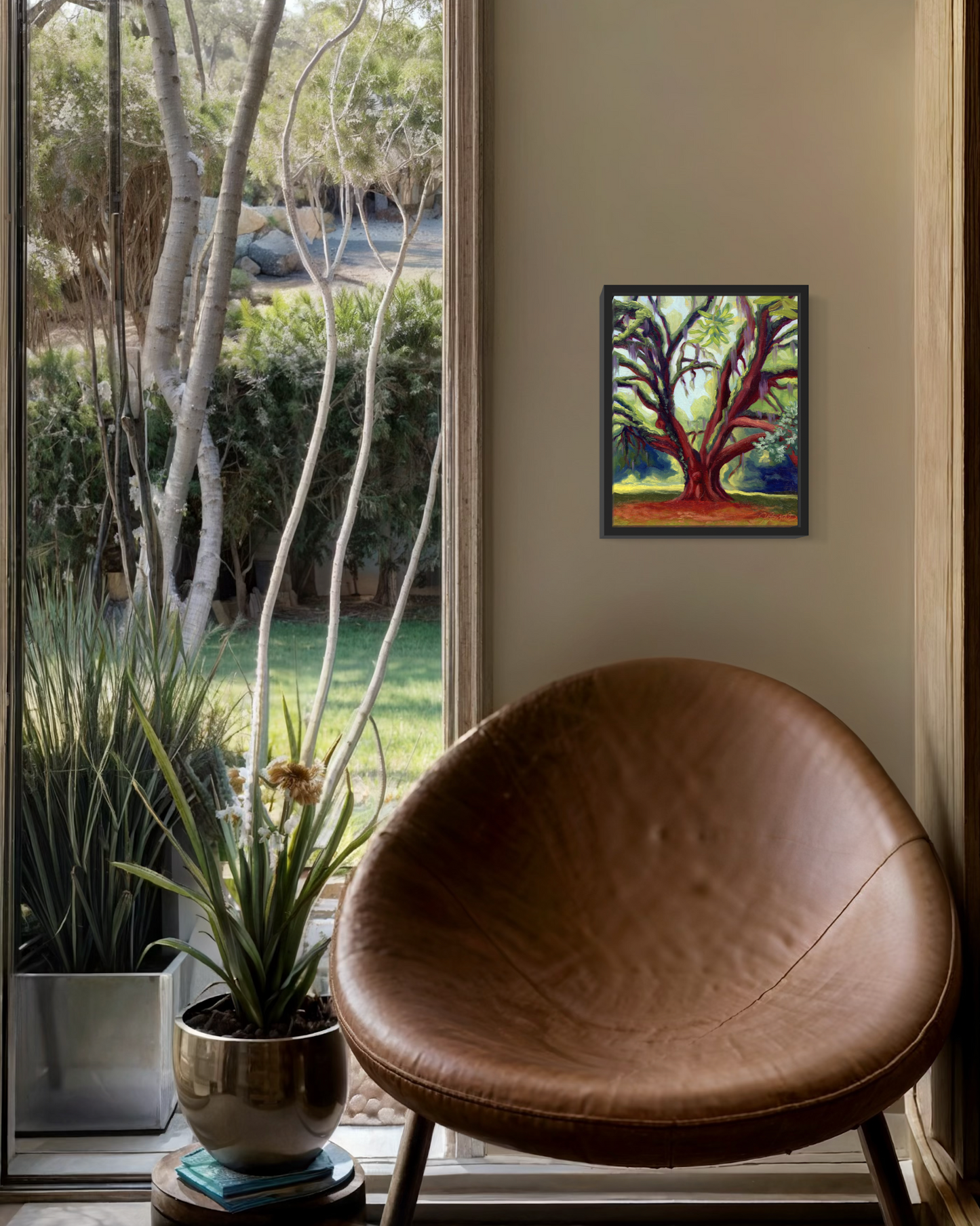 Brown leather chair in a room with a painting of a tree on the wall and a view of trees outside.