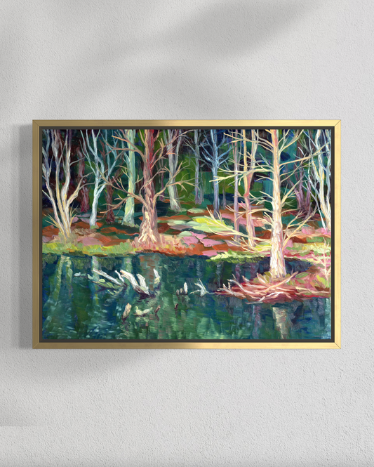 Framed painting of a forest scene with trees and water on a white wall.