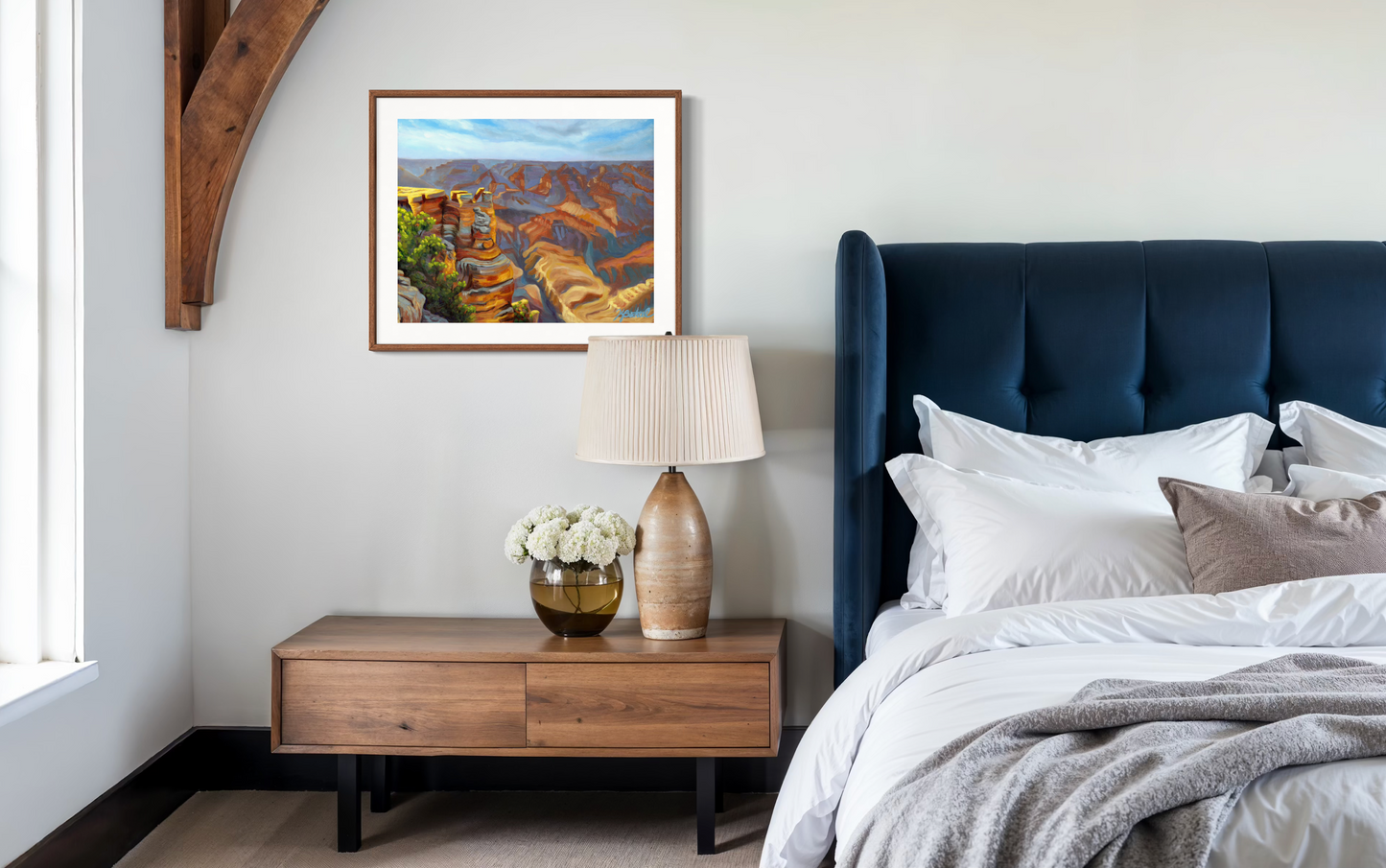Modern bedroom with a bed, nightstand, lamp, and artwork on the wall.