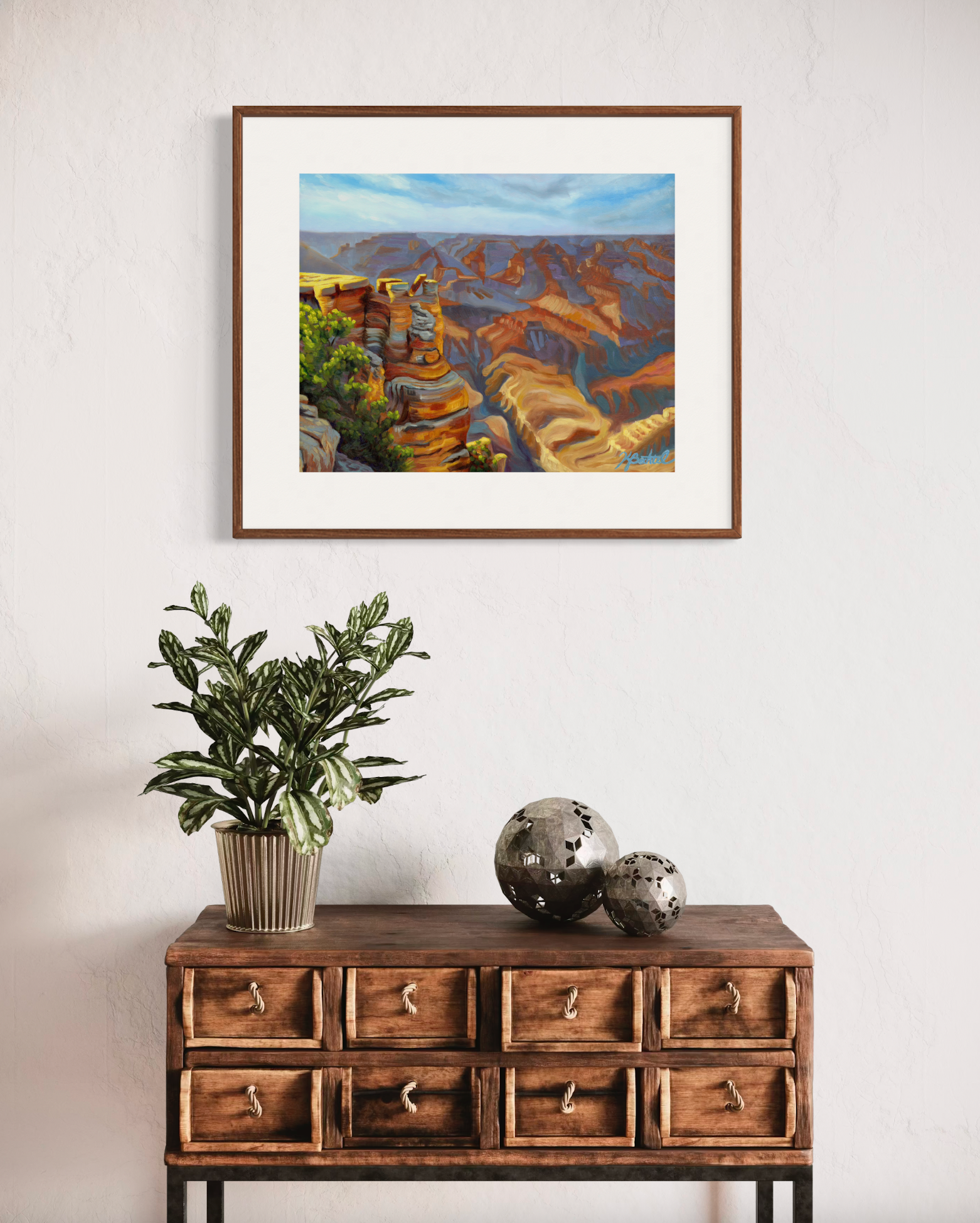 Framed landscape painting above a wooden console table with decorative items.