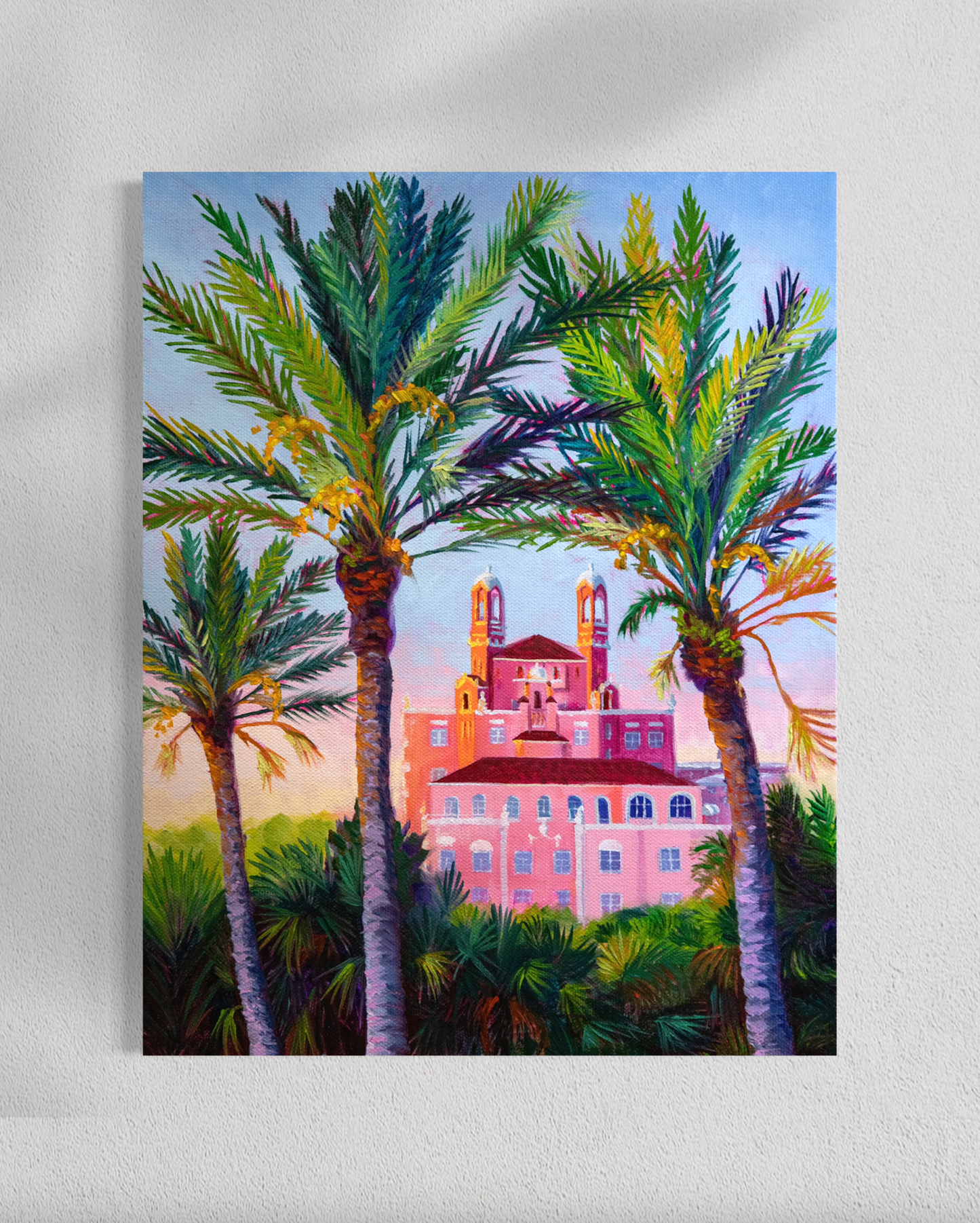 Painting of a pink building with palm trees on a white wall