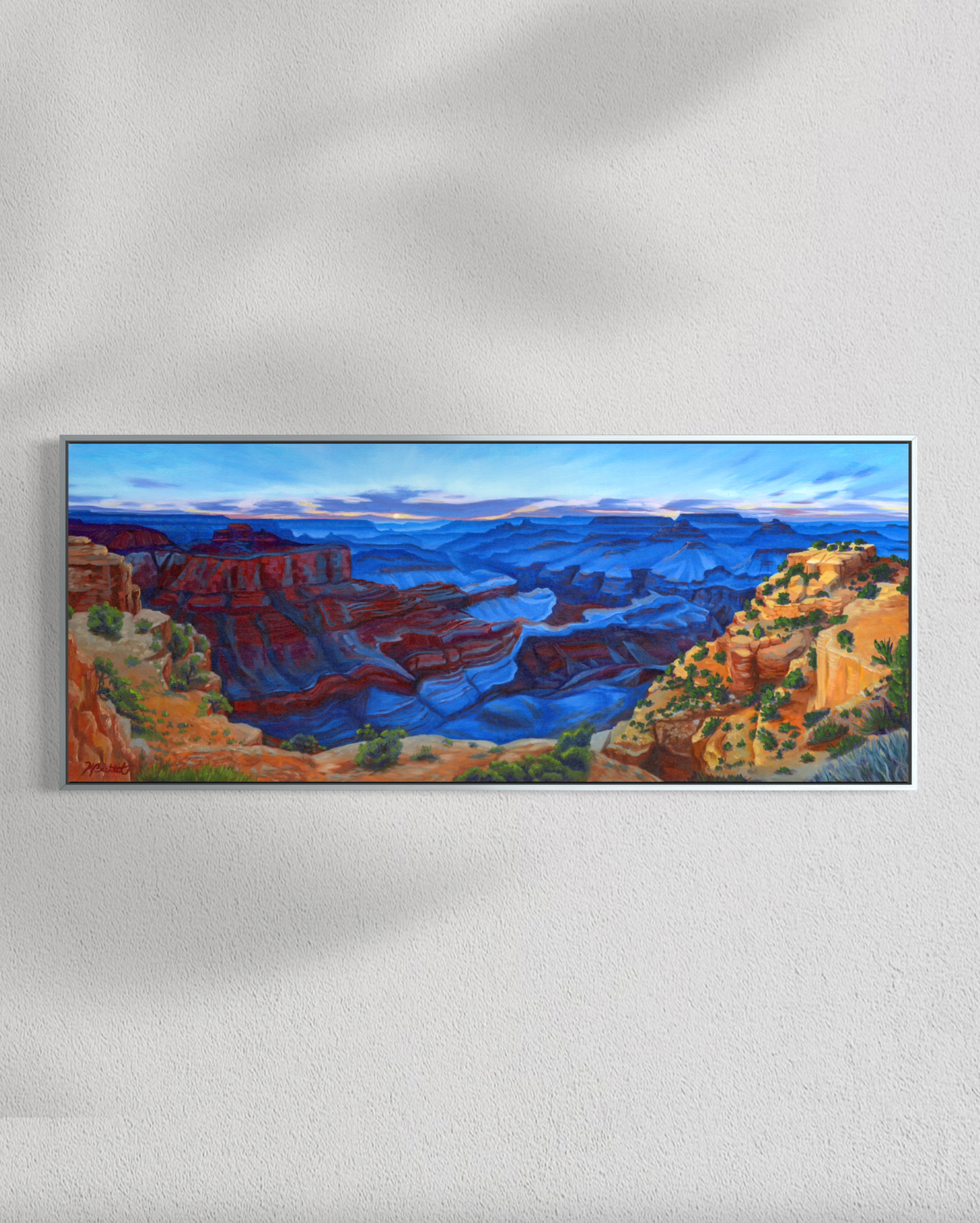 Framed painting of a canyon landscape on a white wall