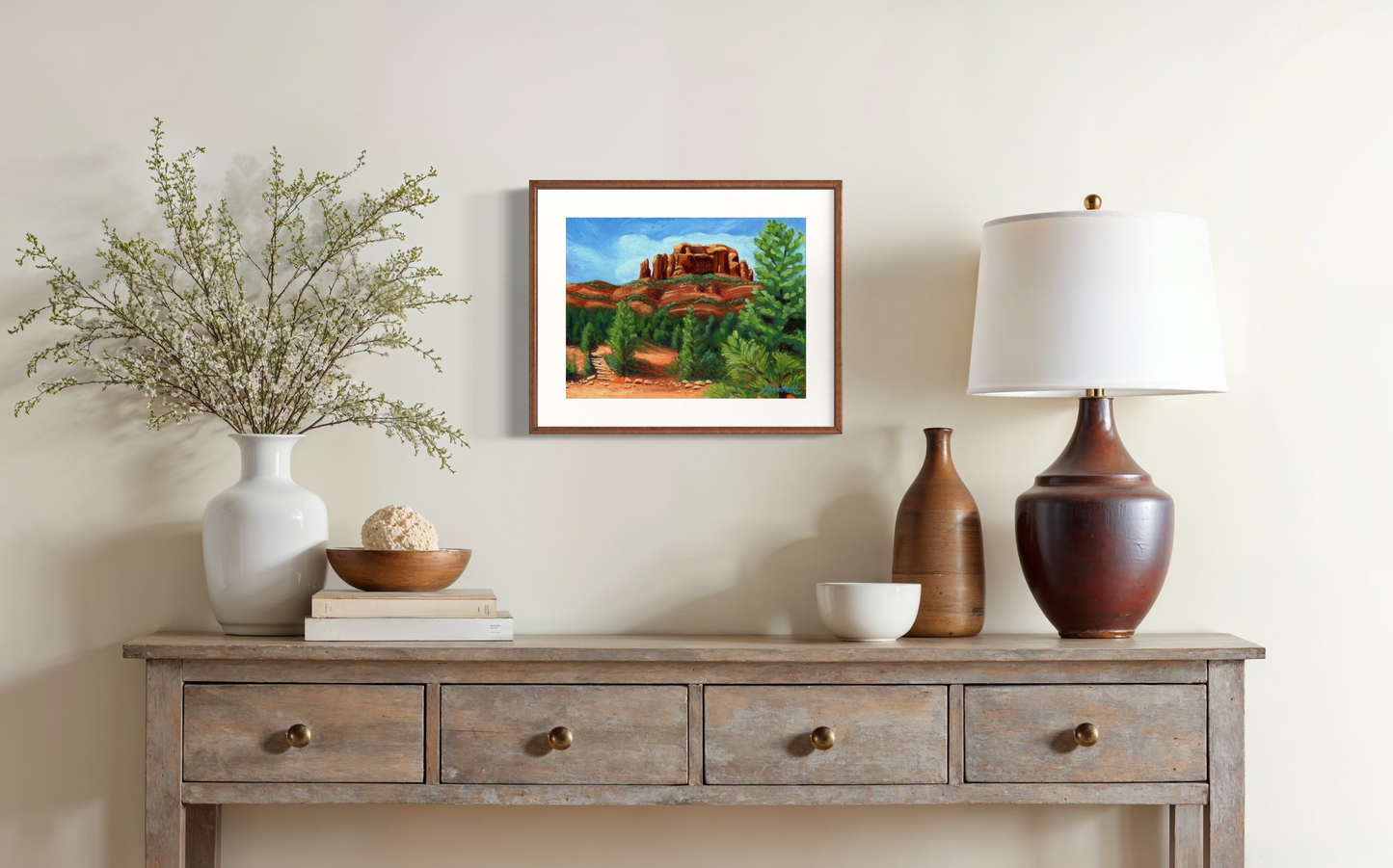 Framed artwork on a wall above a wooden console table with decorative items.