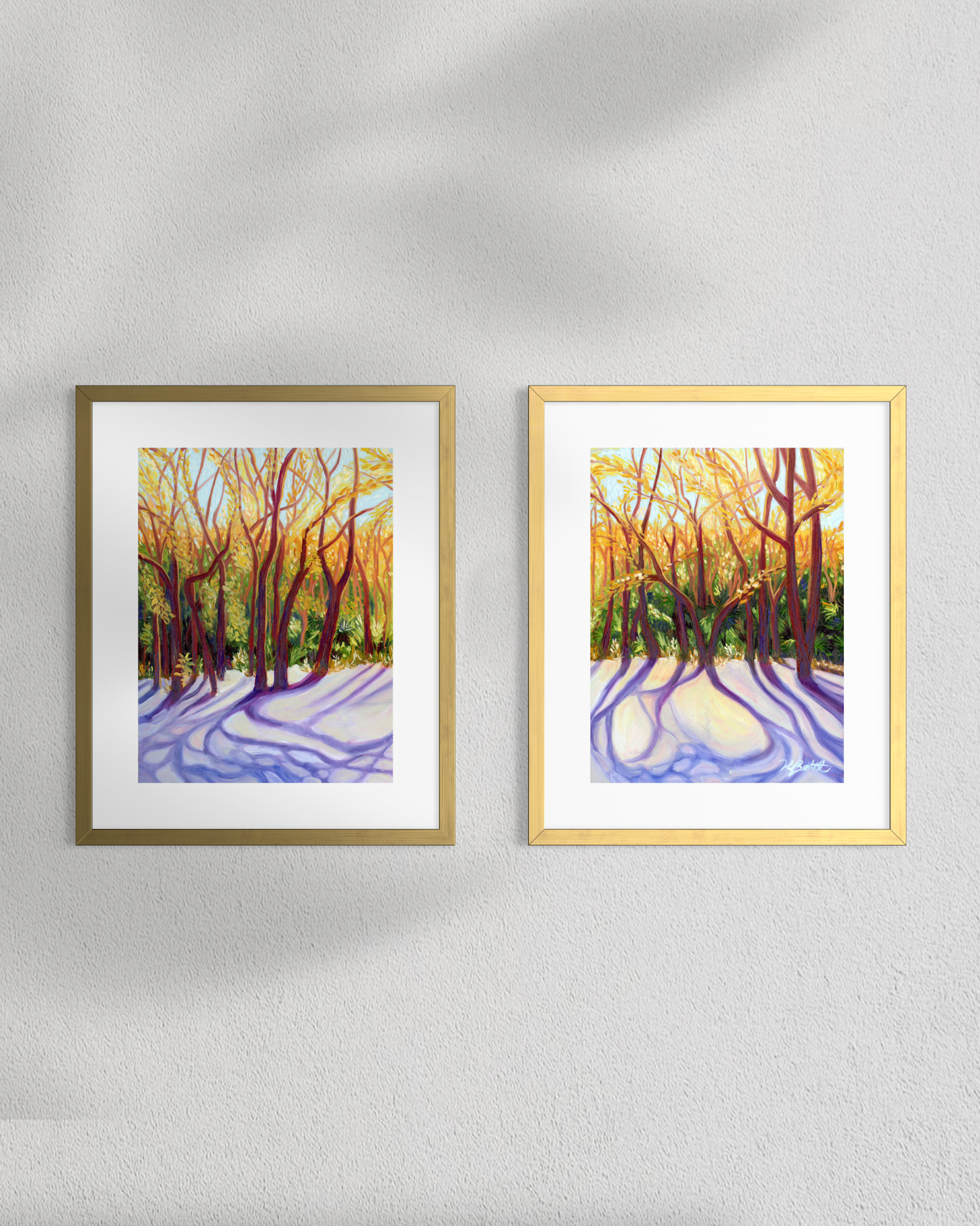 Two framed artworks of a snowy forest scene on a light gray wall.