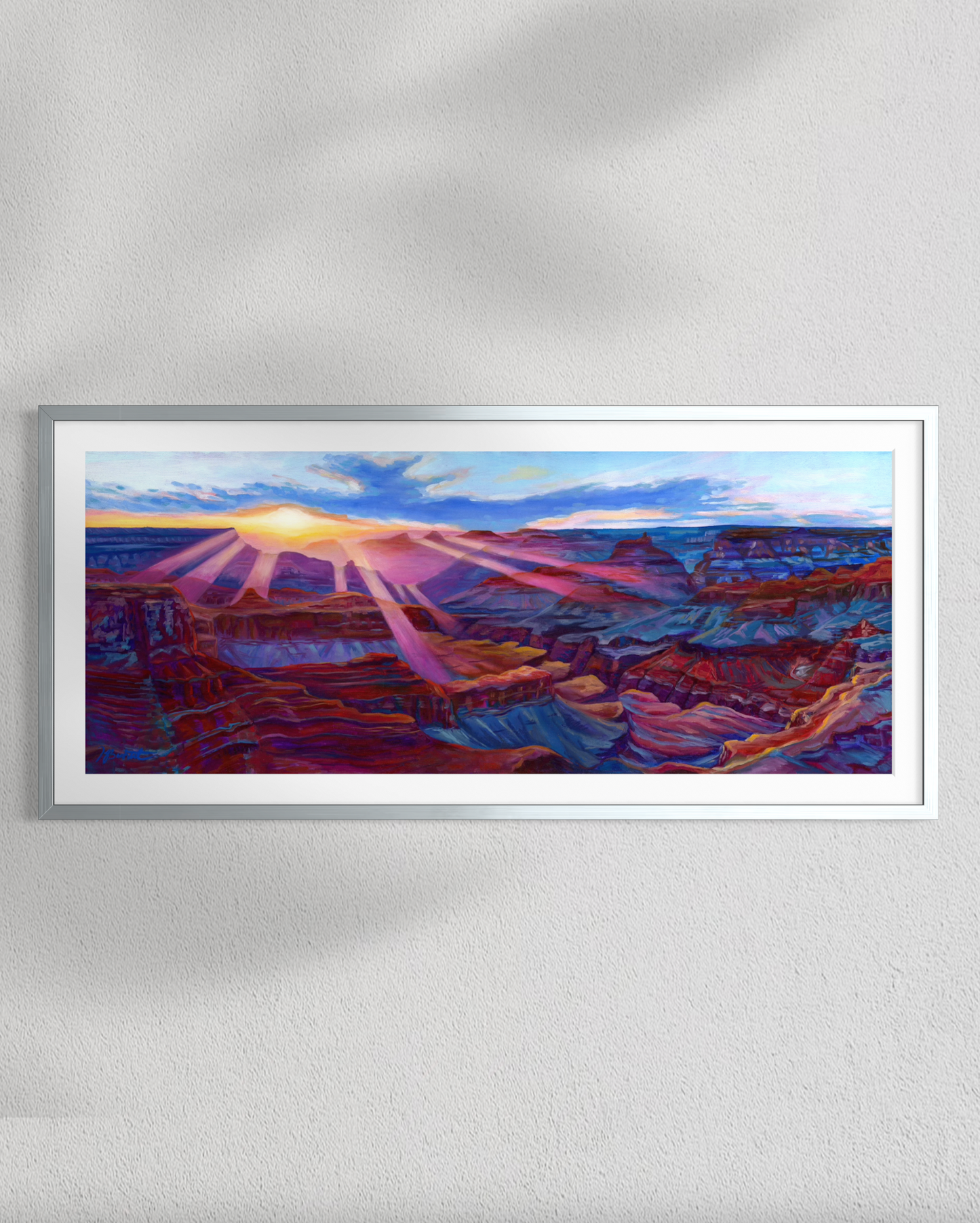 Framed artwork of a canyon landscape with a sunset, on a white wall.