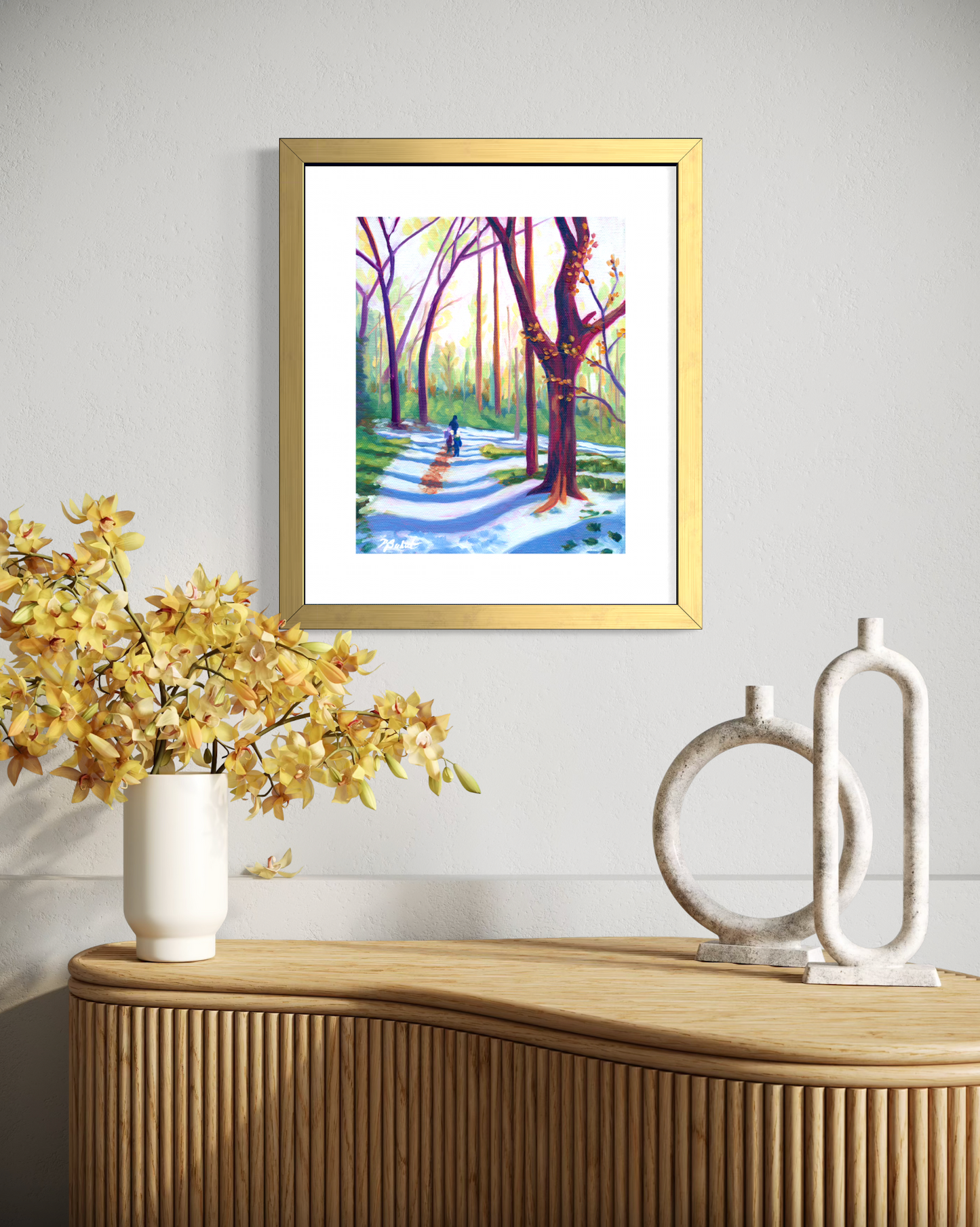 Framed artwork of a park scene on a wall above a wooden console table with decorative items.