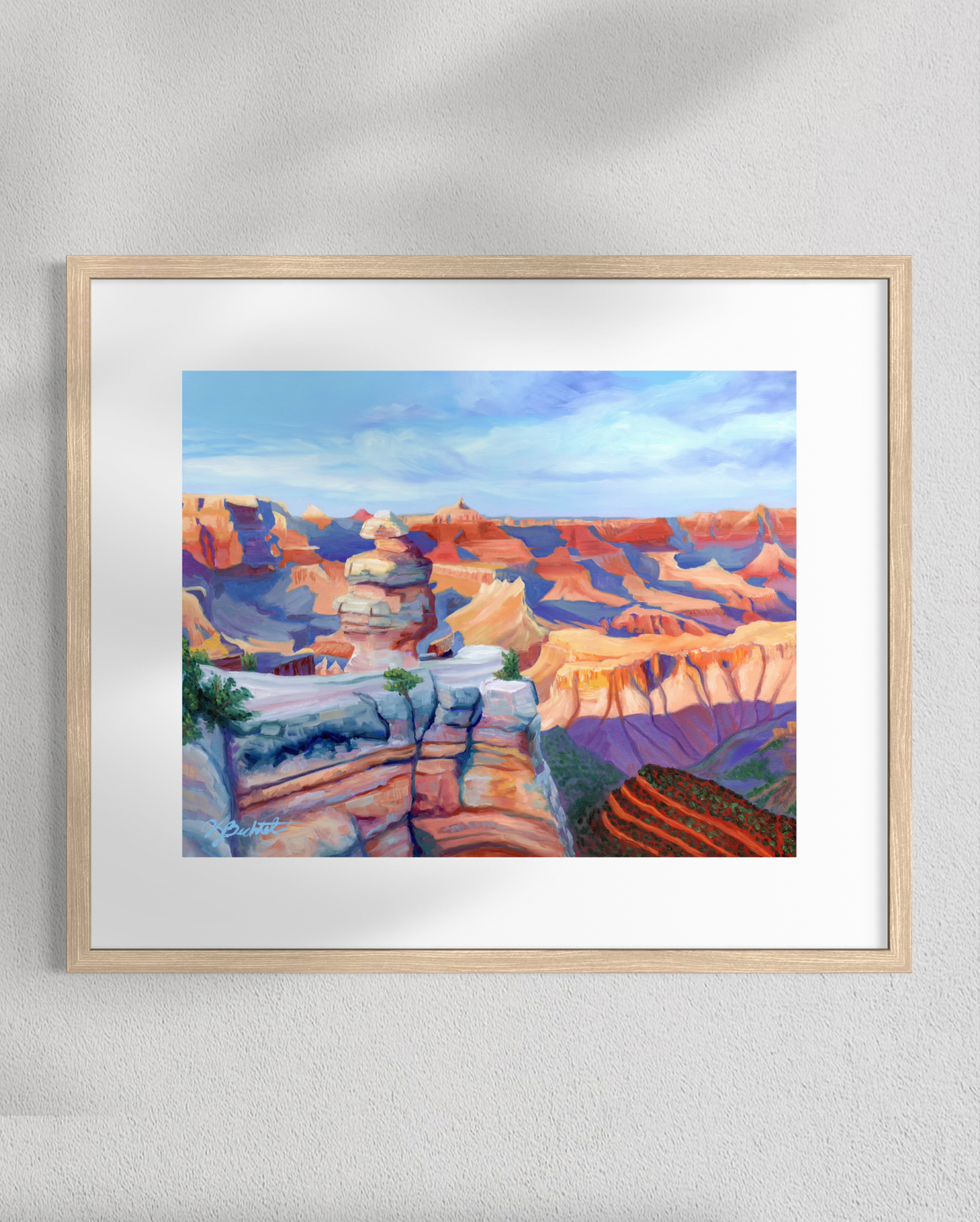 Framed painting of a colorful landscape on a white wall