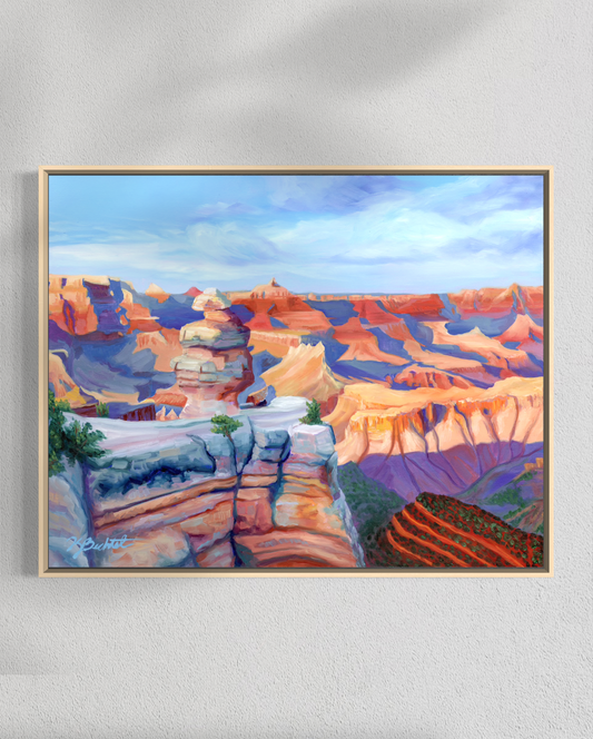 Framed painting of a colorful landscape with rock formations on a white wall.