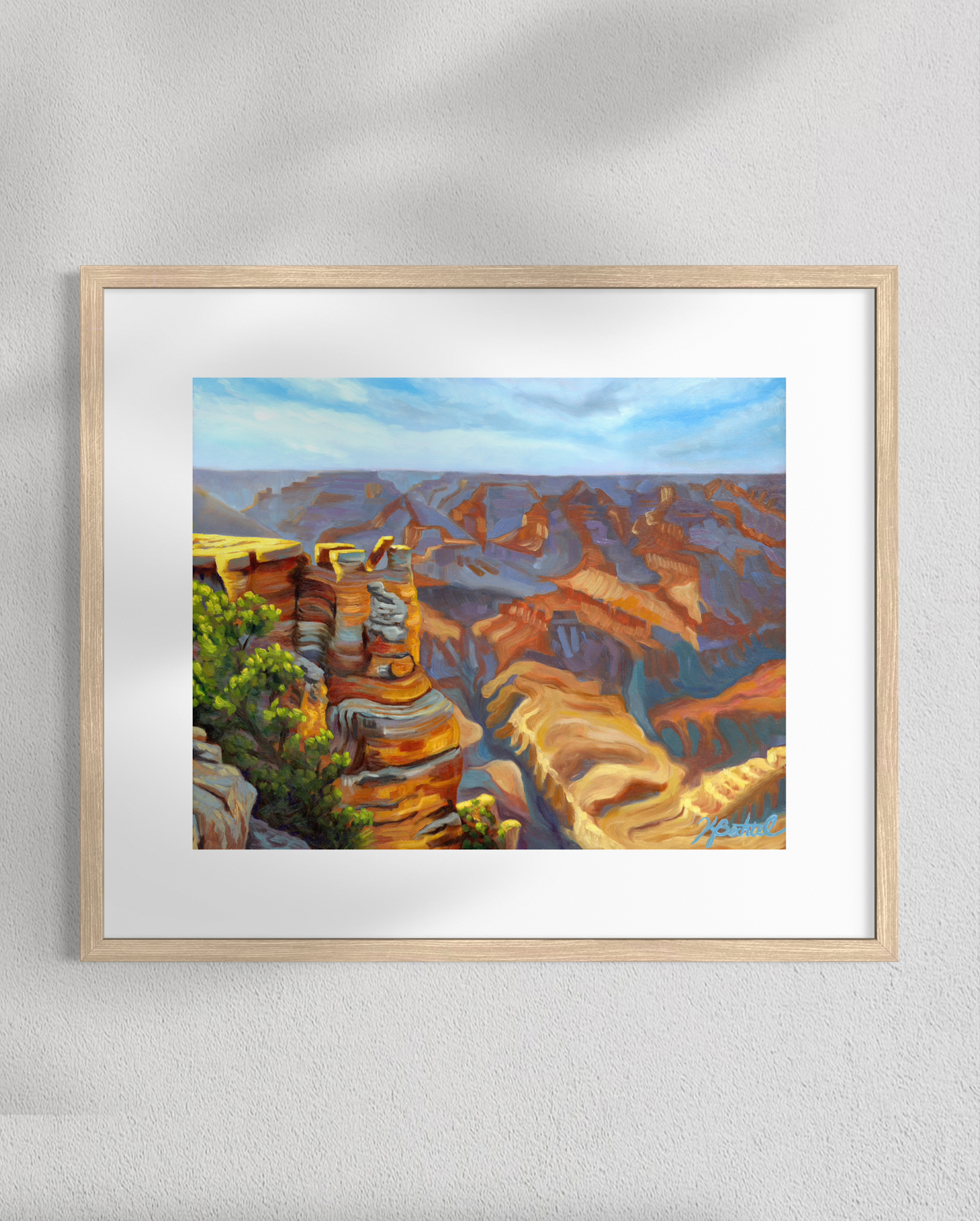 Framed painting of a canyon landscape on a white wall