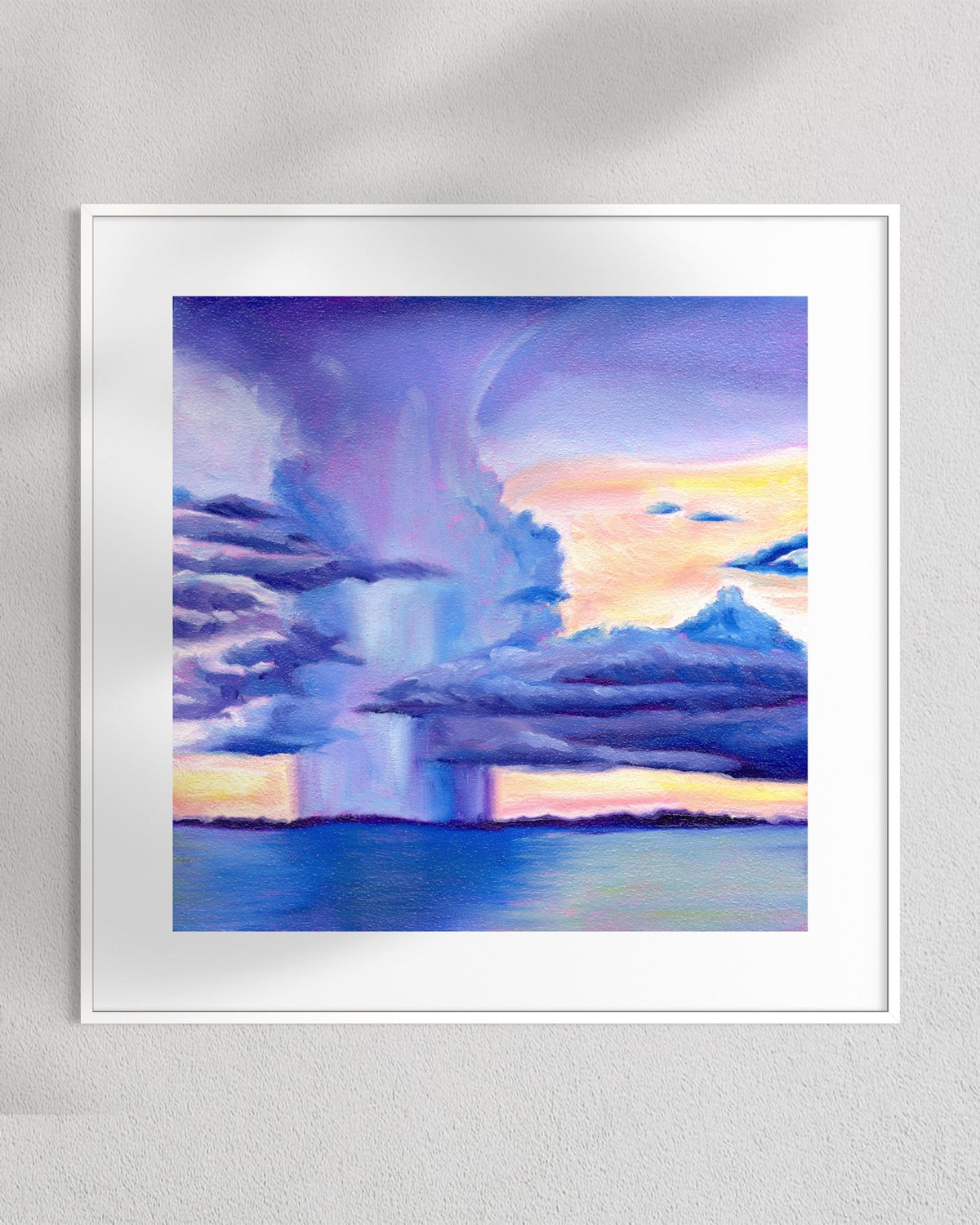 A framed art print depicting a dramatic storm scene with purple and blue clouds, a bright yellow-orange horizon, and a waterfall, mounted on a textured light gray wall.