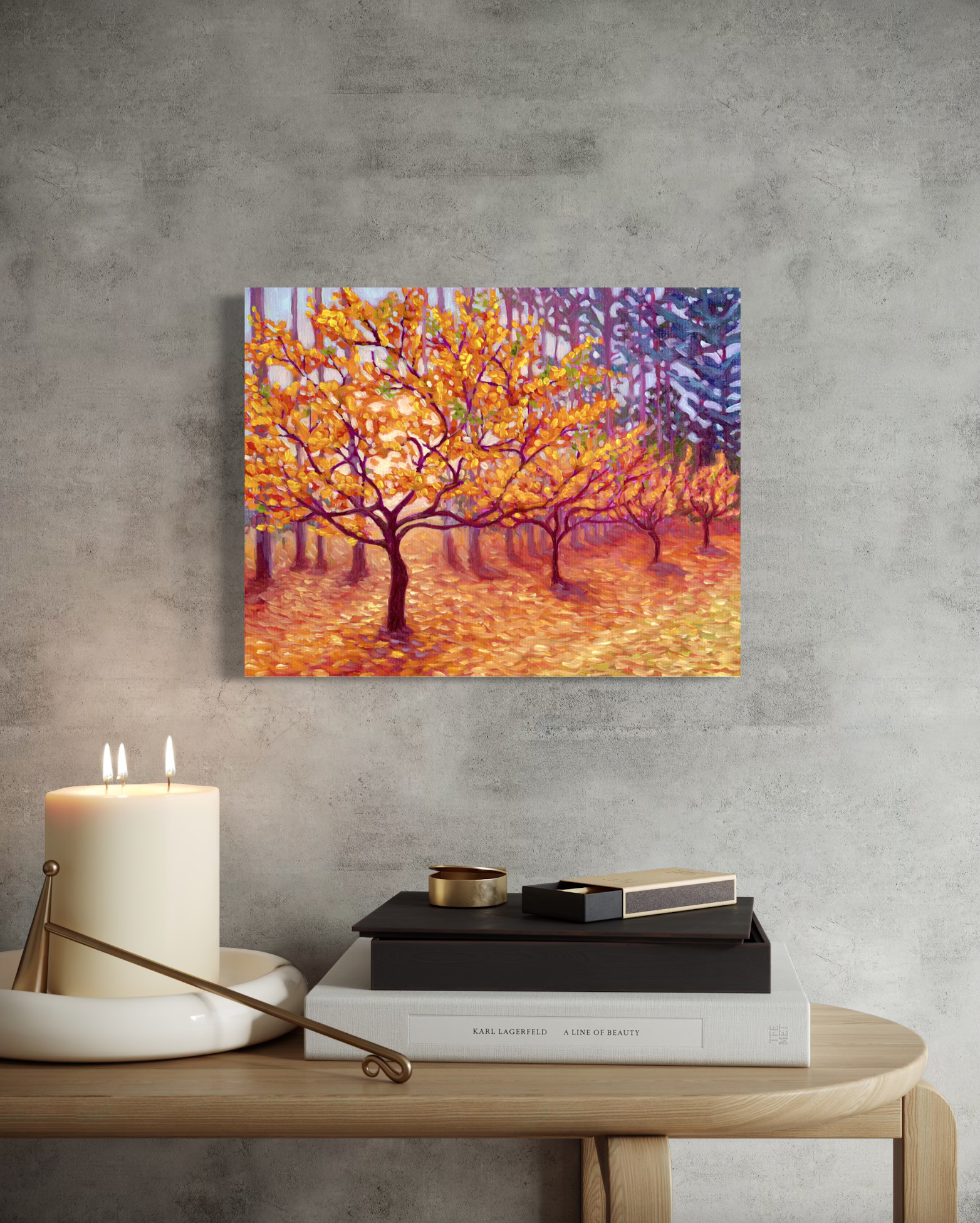 Mockup of Canvas print of artwork showing trees with autumn colors on a gray wall above a table with books and a candle.