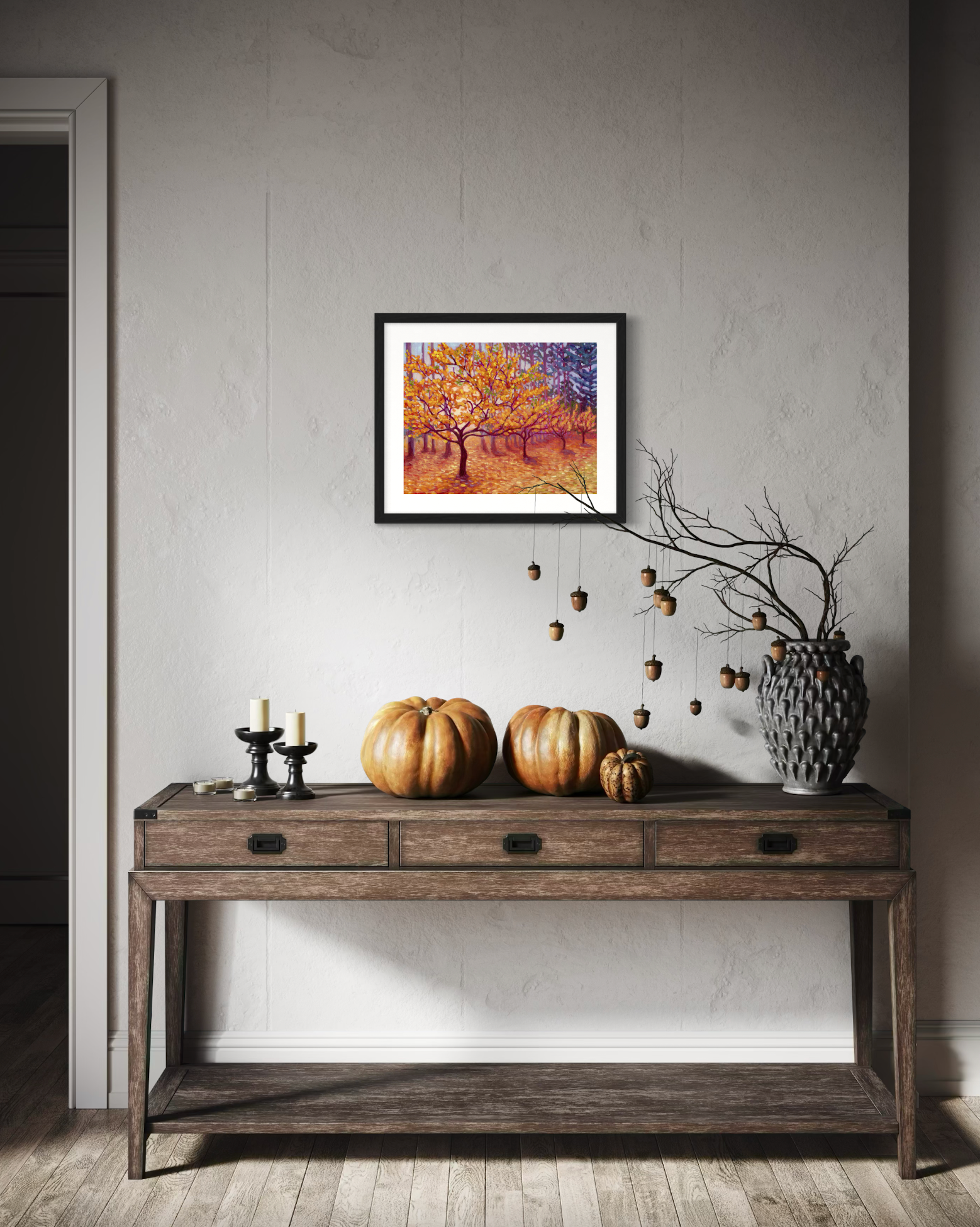 Decorative console table with pumpkins and a framed artwork of golden trees on a wall.