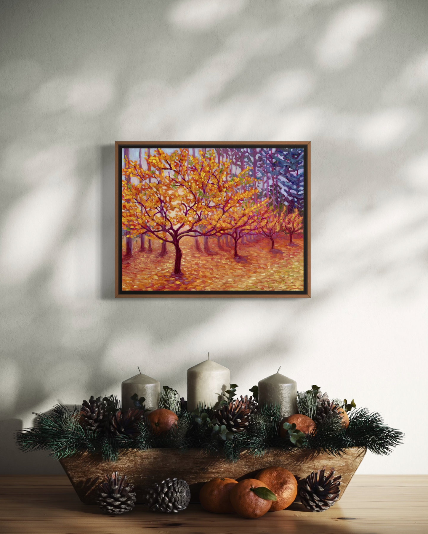 Framed artwork of a tree with autumn leaves above a wooden bowl with candles and decorative items.