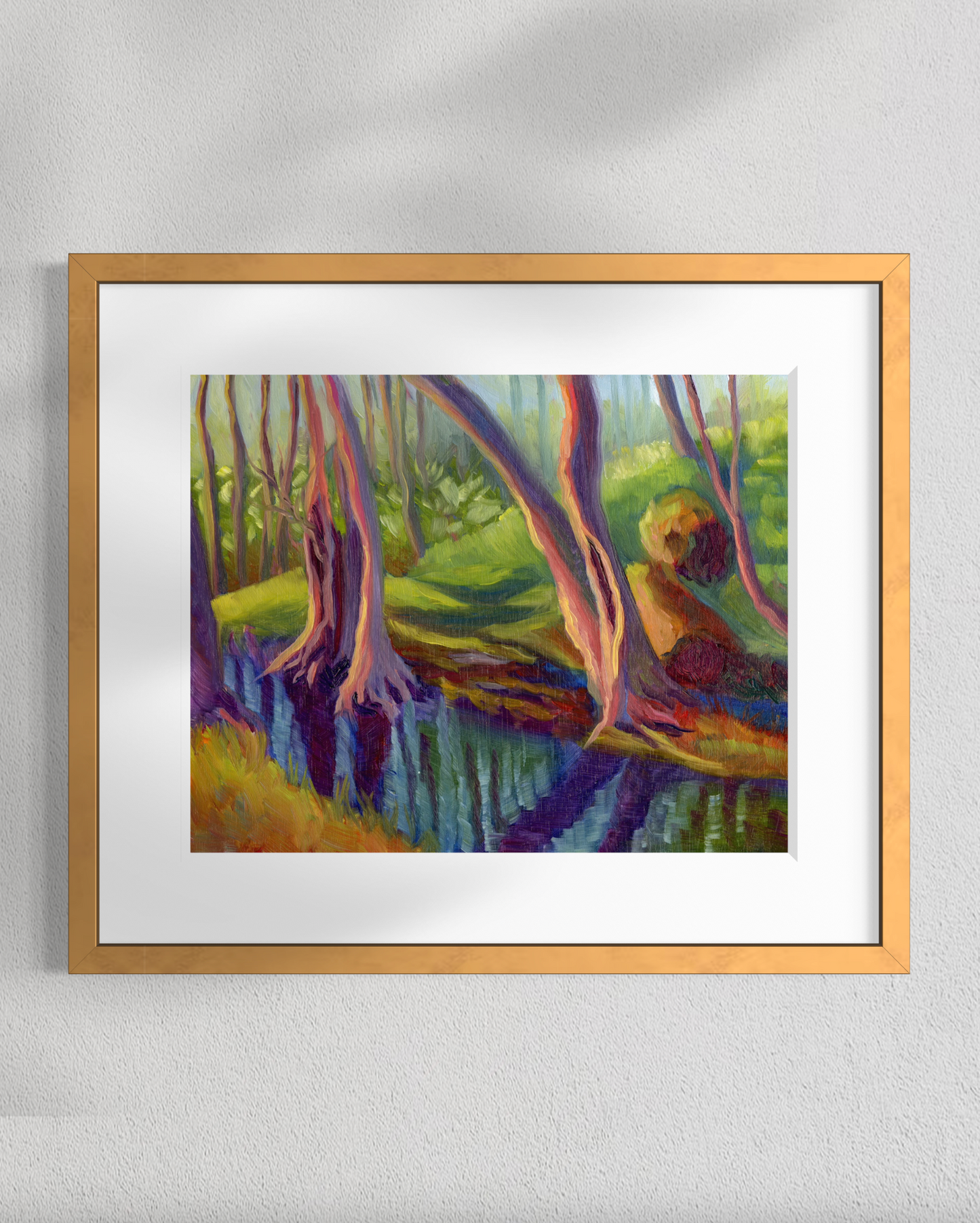 Framed painting of a person sitting by a stream with trees on a gray wall