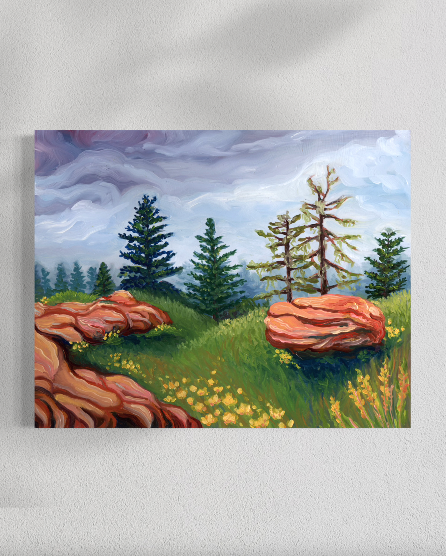 Painting of a landscape with trees, rocks, and grass on a white wall.