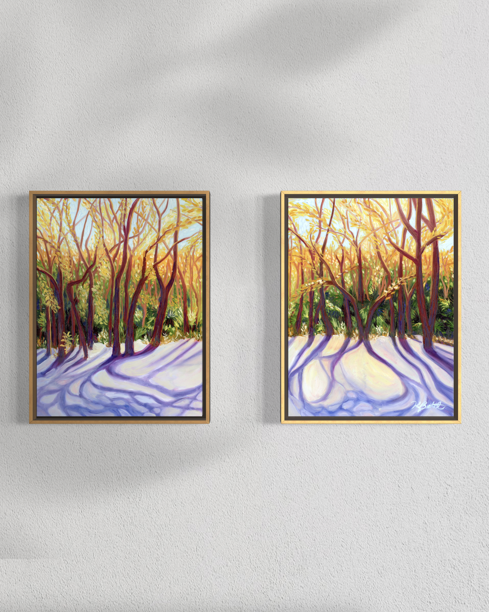 Two framed paintings of a forest scene with sunlight on a white wall.