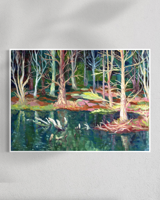 Framed artwork of a forest scene with trees and water on a white wall.