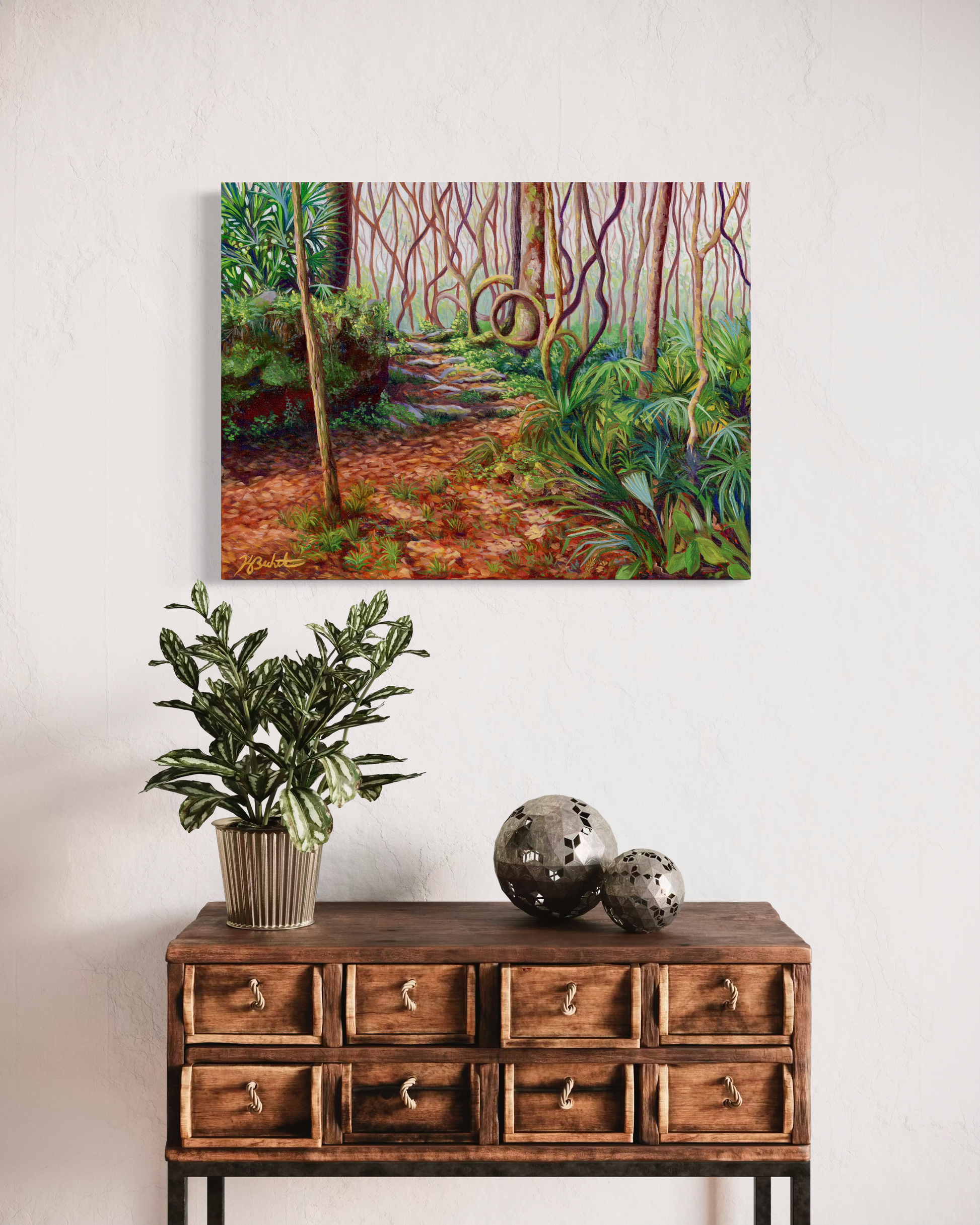 Wooden cabinet with a plant and decorative balls, featuring a forest painting above.