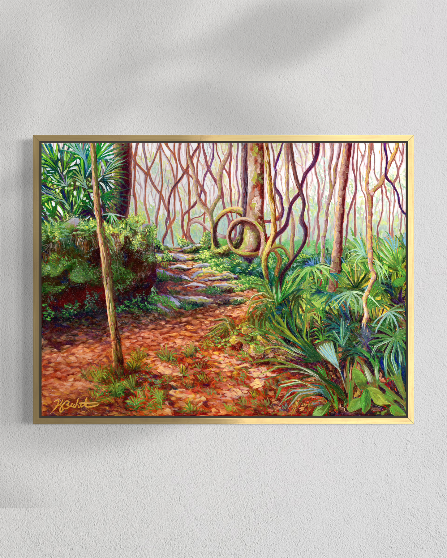 Framed painting of a forest path with vibrant greenery on a white wall.