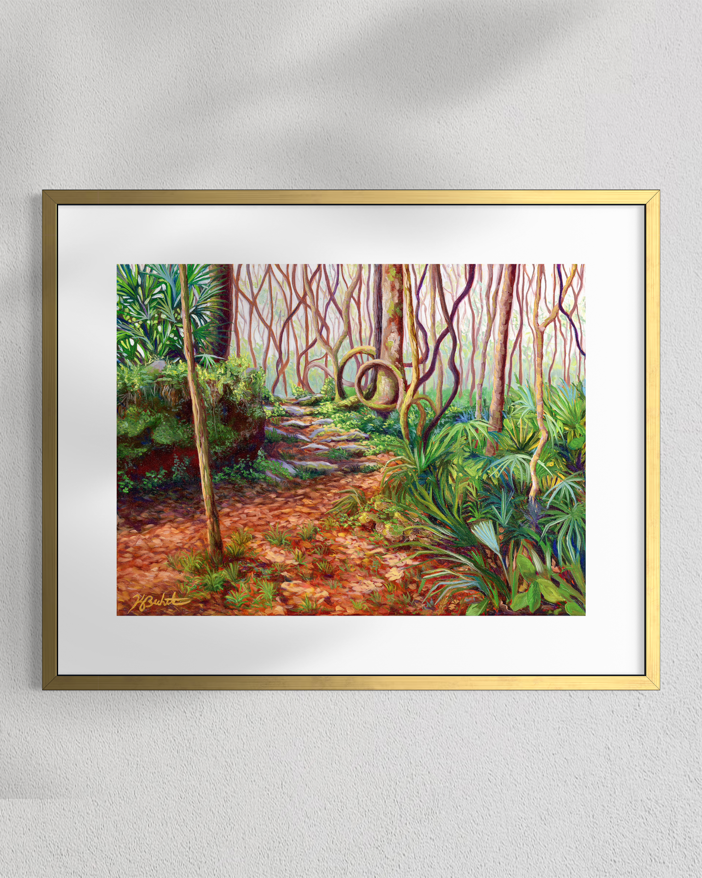 Framed painting of a forest path with vibrant greenery on a white wall.